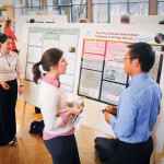 Student in front of poster talking to man