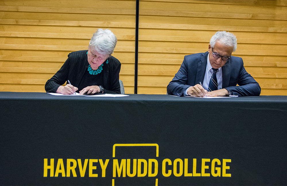 Man and woman sit at table signing documents