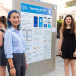 Students stand in front of research poster