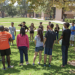 Summer Institute students form a circle outside on campus