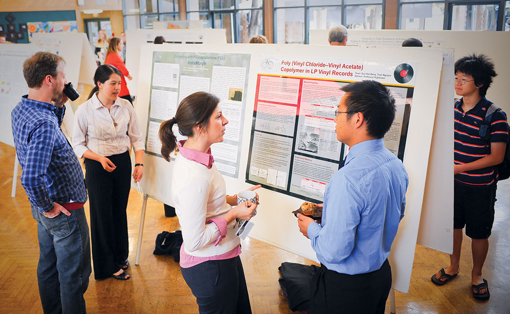 Student in front of poster talking to man