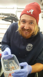 Mike Adams holding a coral specimen in a container.