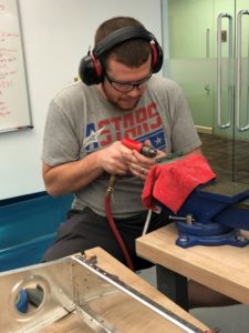 Student drilling fuel tank brackets in lab