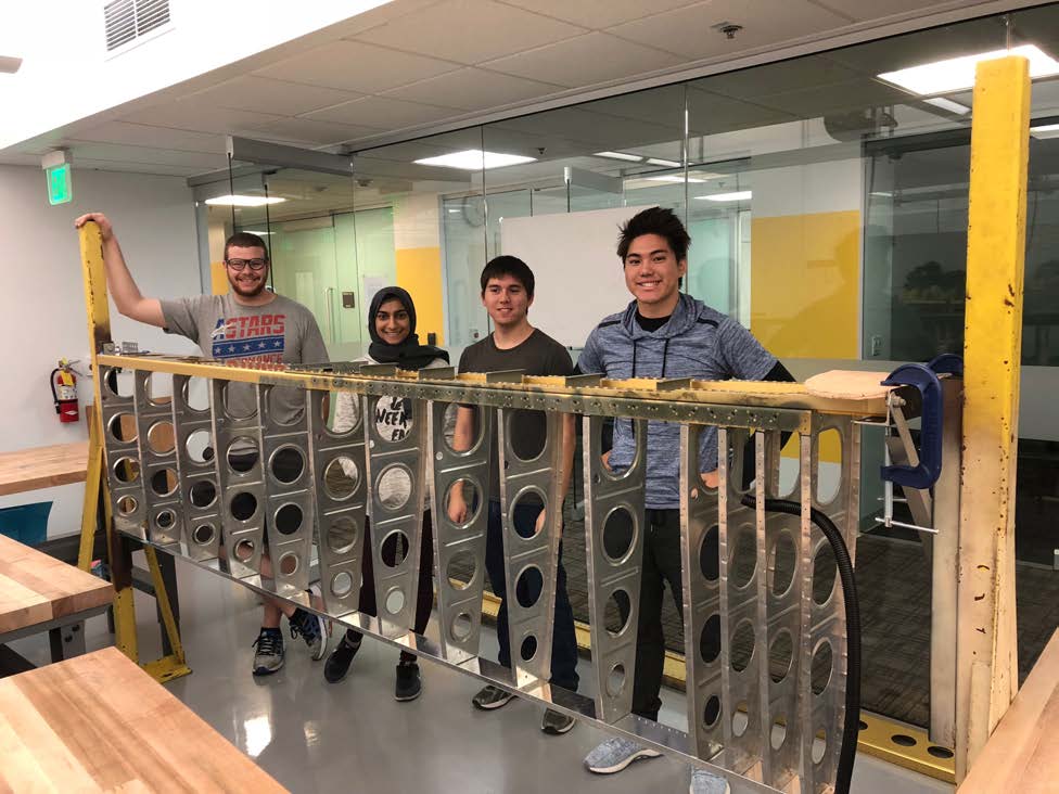 student interns with airplane wing skeleton in lab