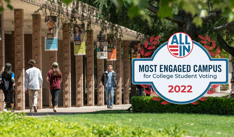Students walk in front of Harvey Mudd architecture. The ALL IN seal for Most Engaged Campus for College Student Voting 2022 appears besides them.