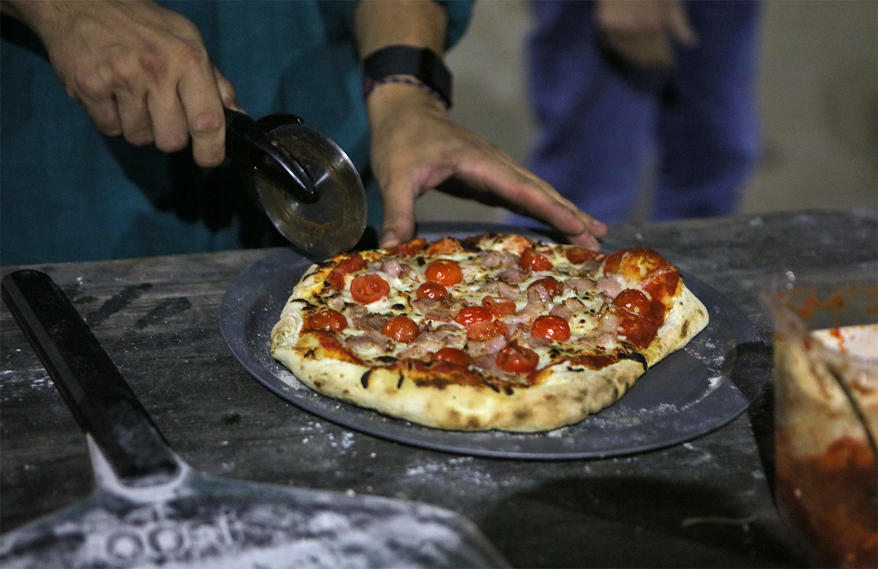 A tomato and cheese pizza is cut with a pizza wheel