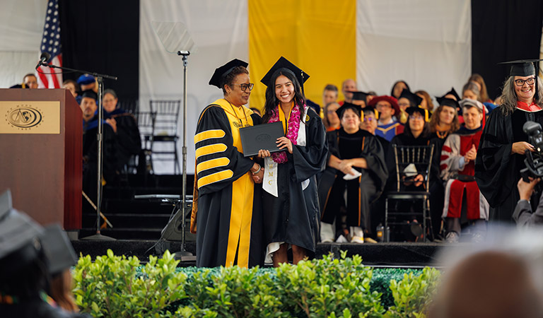 Student receives diploma from President Nembhard