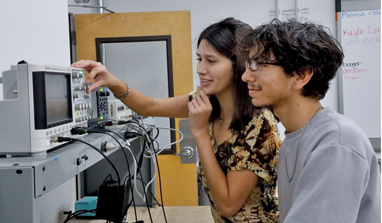 Harvey Mudd students Sofia Flores ’27 and Joaquin Gonzalez-Salgado ’28 adjust an oscilloscope to analyze an electrical signal.