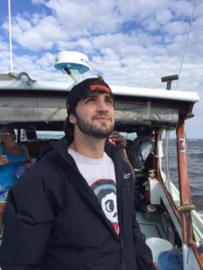 Grant looks up at the sky pensively from a boat