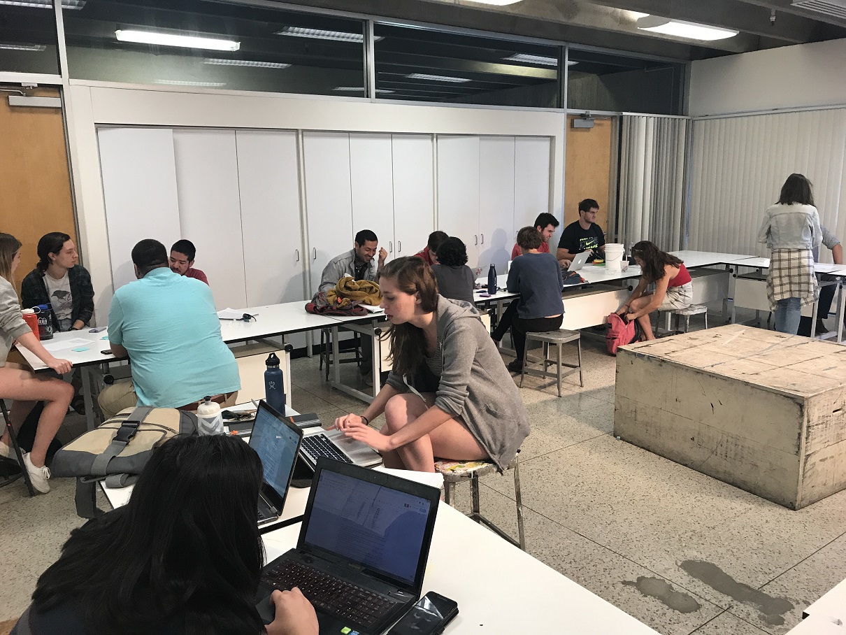 Students talk in small groups and work on their laptops in the Game Design class.