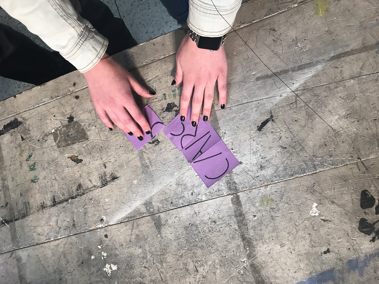 A student puts together pieces of paper with parts of letters on them
