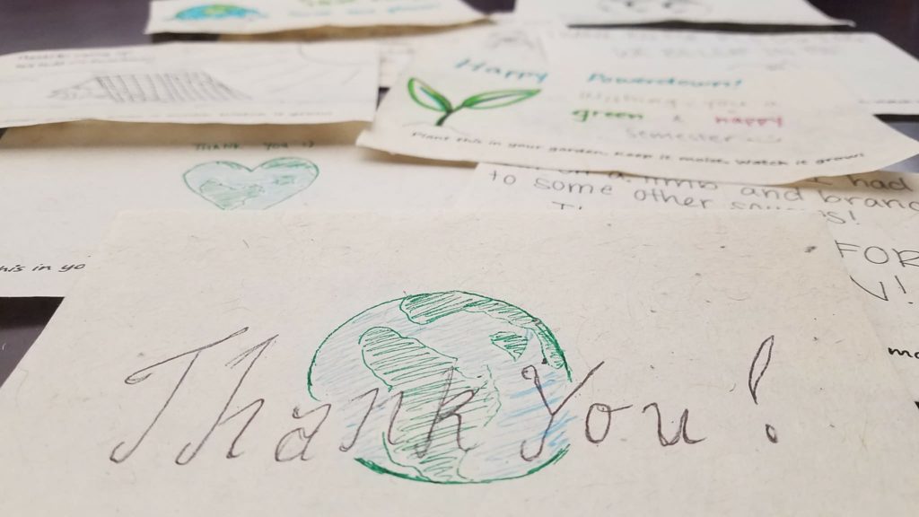 Various envelopes laid out on a table, the closest one reading Thank You over an image of the earth.