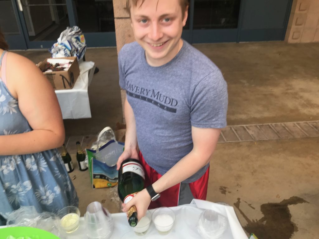 Blake, smiling, pouring a glass of champagne.