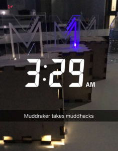 Three wooden boxes with plexiglass “M”s standing on top sit on a table. Text on the image says “3:29AM”