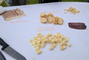 A piece of butcher paper with baguette slices in the center, and piles of small cheese cubes and slices of cured meats