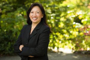 Picture of Dean Gonzalez in a black blazer. Foliage in the background.