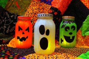 A picture of three jars, which have been decorated to look like a carved pumpkin, a cartoon ghost, and a cartoon Frankenstein.