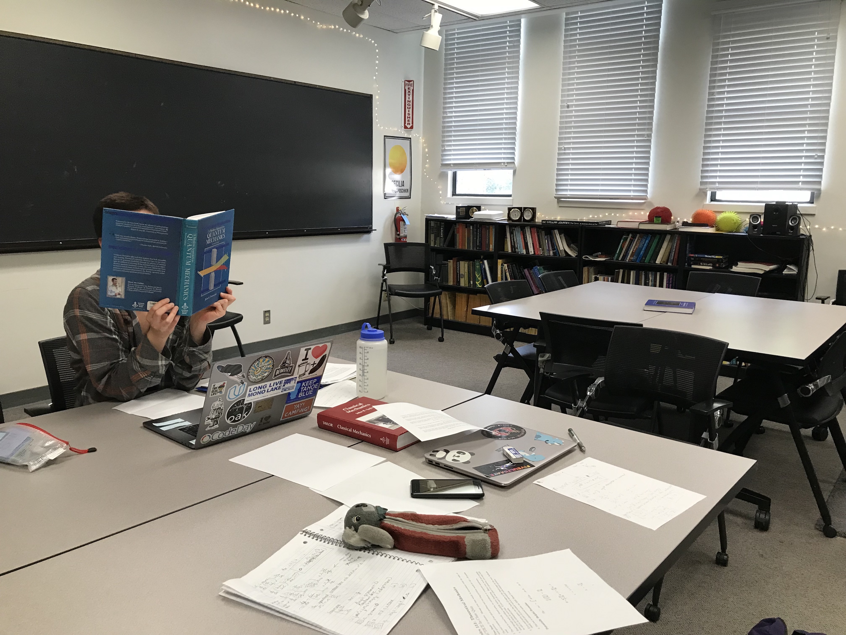 Friend Rachel reading a physics textbook; work is spread all over the table