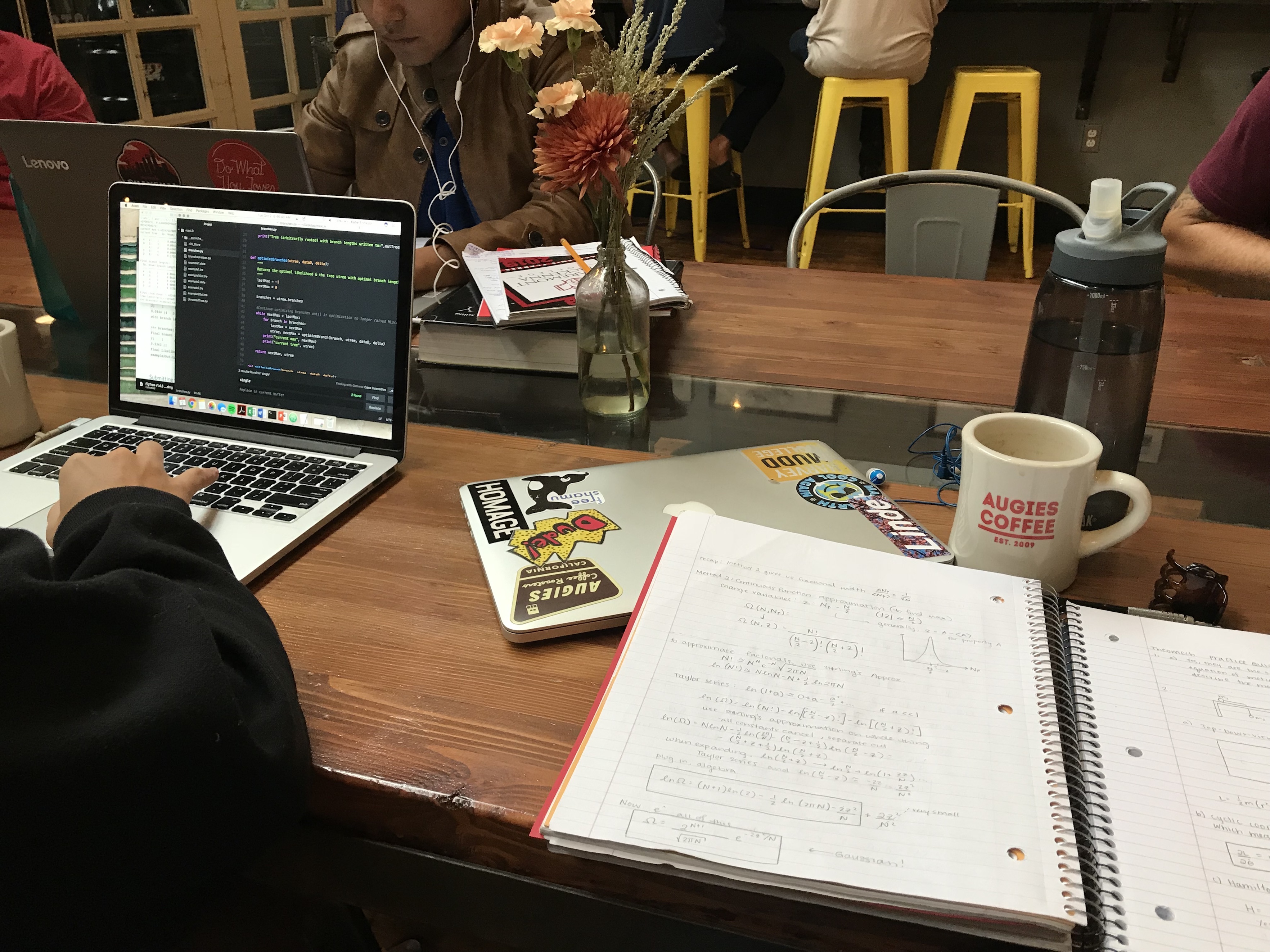 Friend Katie is on the left working on her laptop; notebook open with physics notes for studying