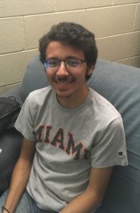 Medium shot of Kalani Dúran smiling, sitting on a couch. 