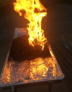 The picture shows the same mound of coals on fire, except in this picture, the fire was doused with lighter fluid just a few seconds ago, so the fire is particularly bright and impressive.