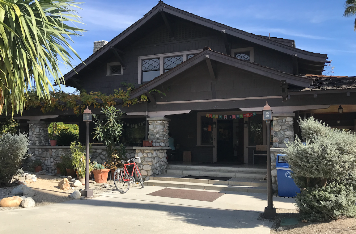 Front of the Grove House at Pitzer; the grove house is an old craftsman style house with a large front porch and seating for eating and doing work