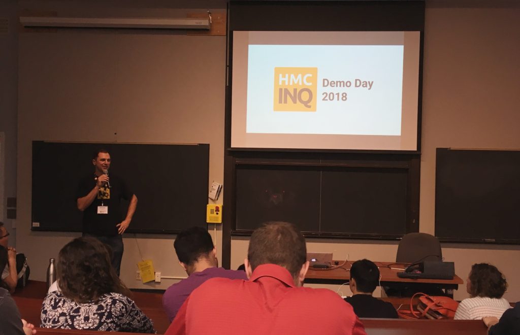 A man stands in front of a slide that says "HMC INQ Demo Day 2018"