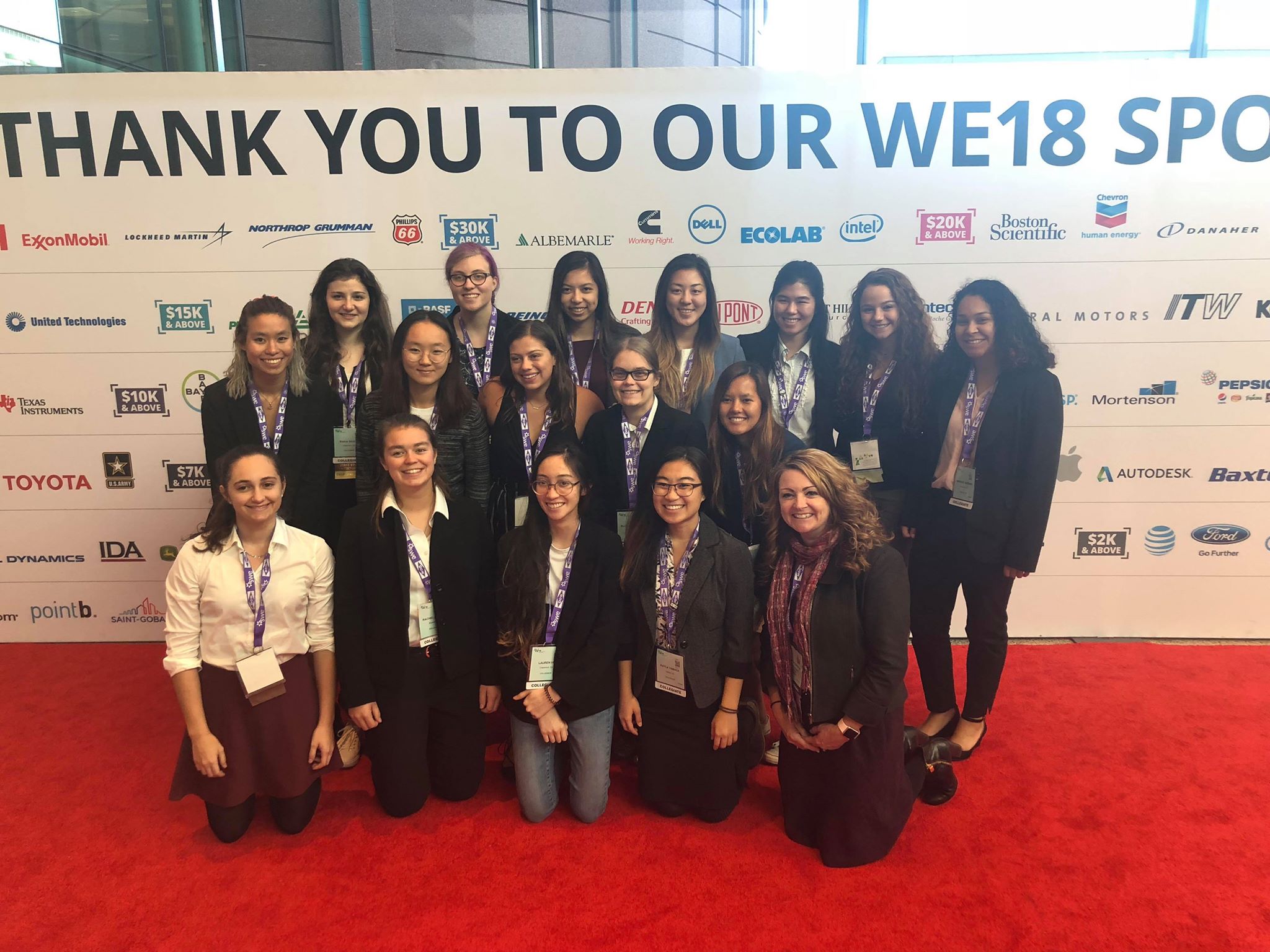 A group of 16 Mudd women engineers at the conference with Mudd professor, Elizabeth Orwin, posing in front of a backdrop for photos.