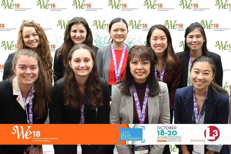 Seven of the SWE members posing in a photo booth with a lady from industry.