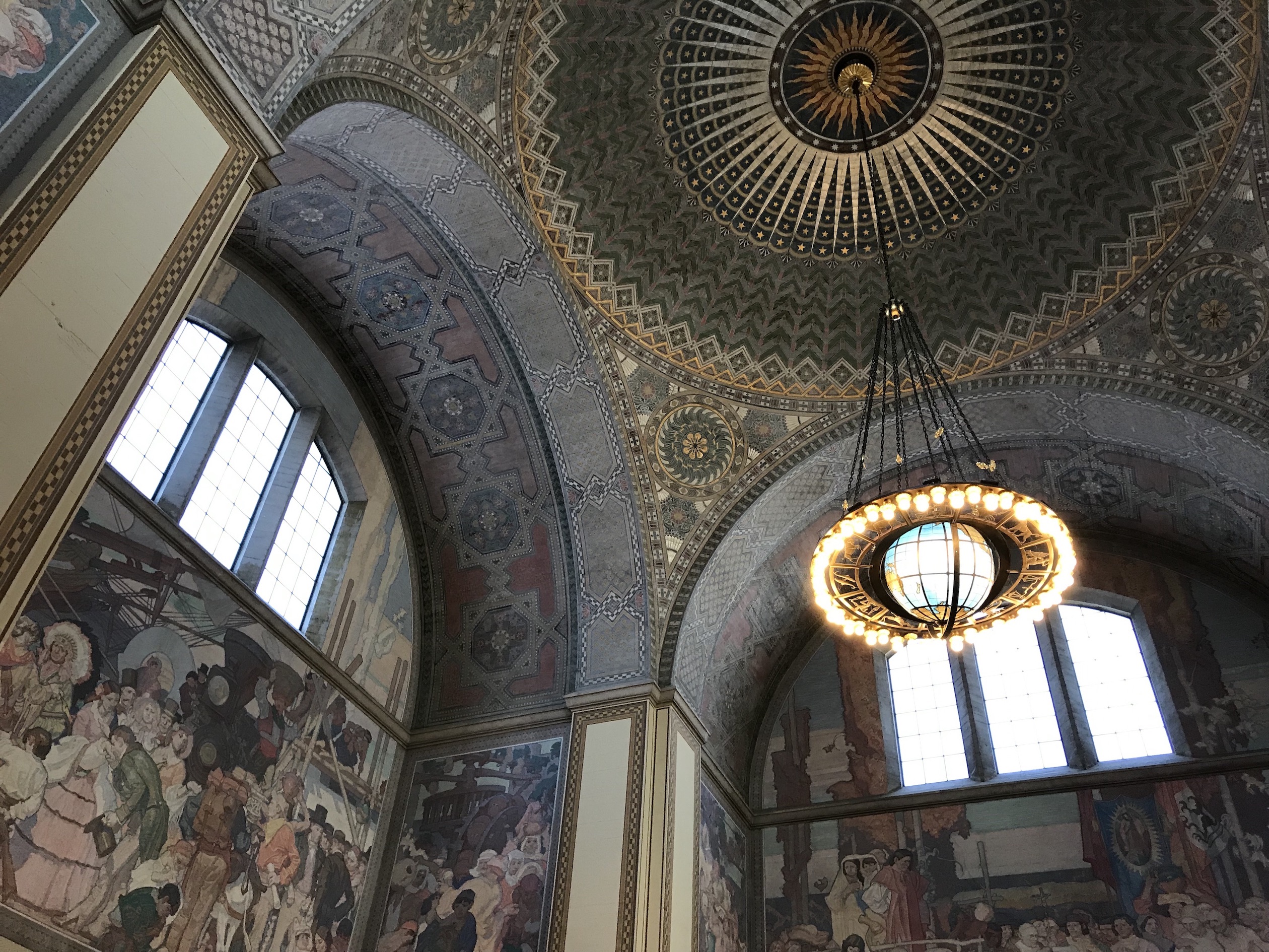 This space has a mosaic tile ceiling and a globe chandelier. Large windows provide lots of natural light