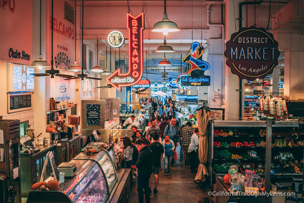 Grand Central Market is packed with people; lots of colorful signs hang from the ceiling for each food booth