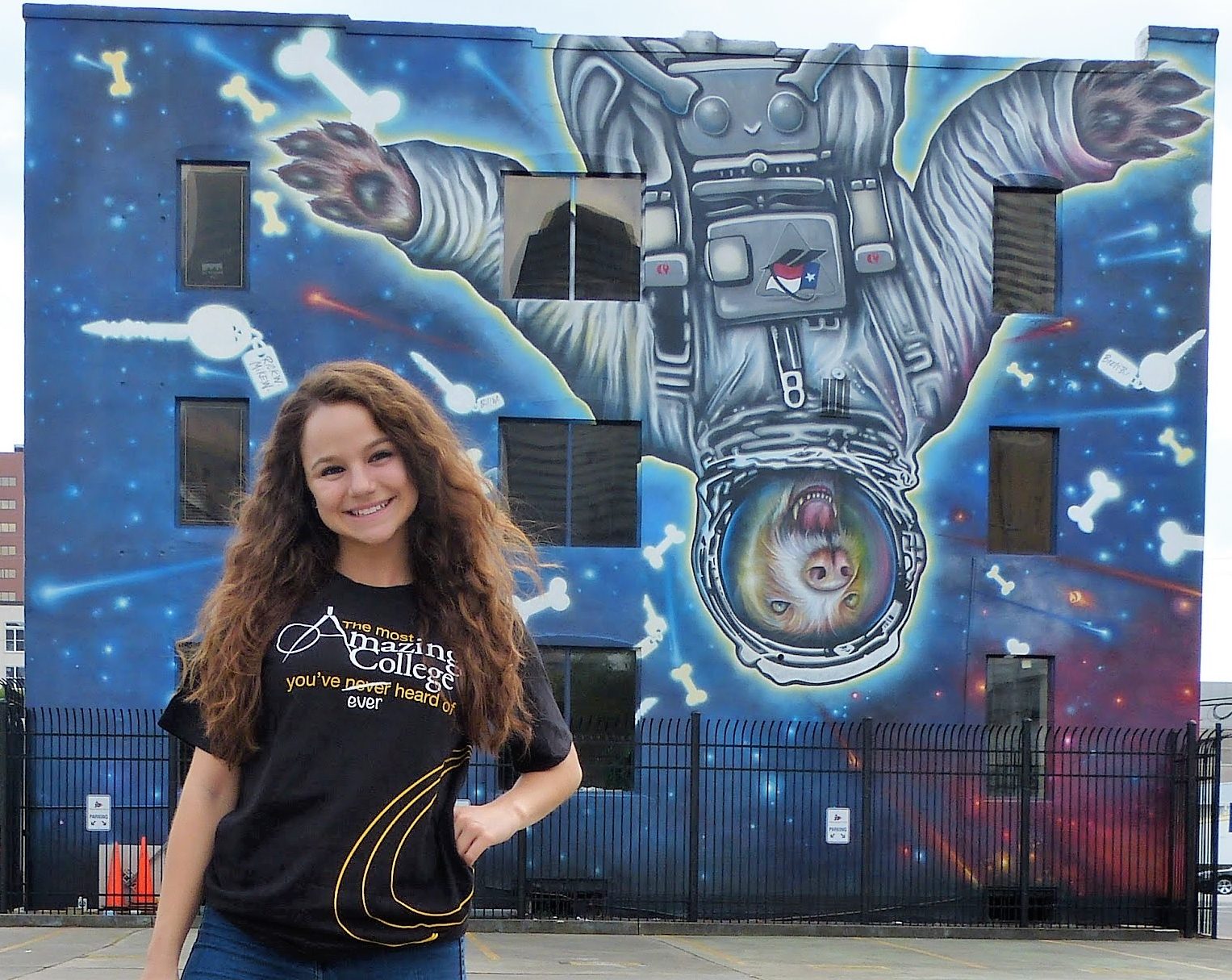 A photo of me wearing a Harvey Mudd Shirt in front of a graffiti decorated wall.