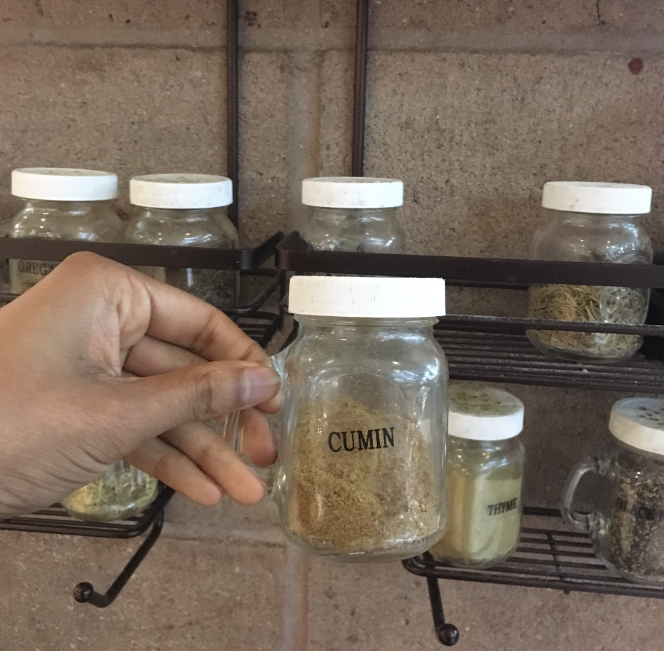 Neeta is holding the shaker jar of cumin from the seasoning bar