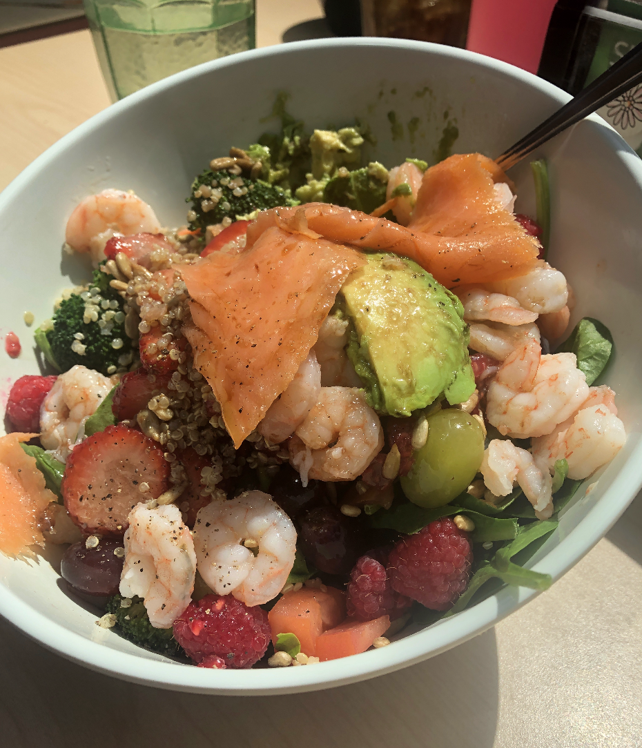 A pre-shaken salad with shrimp, smoked salmon, berries, avocado, quinoa, grapes, and tomato