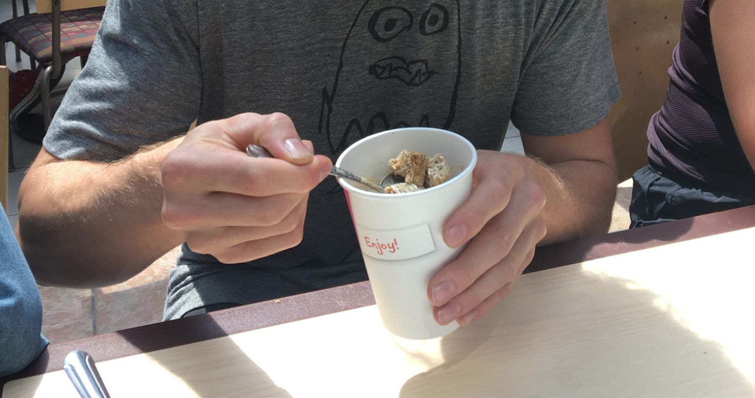 Isaac is eating a cup full of frosted mini wheats and coffee
