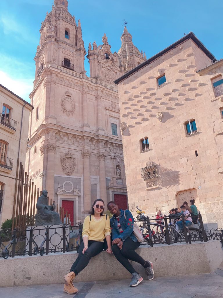 Jasmine and Soluchi sitting in front of a Spanish tower