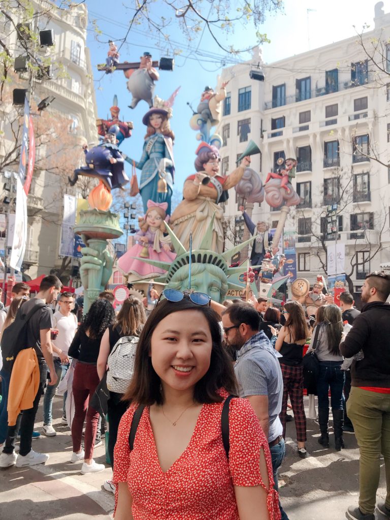 Jasmine and a crowd in front of a large, colorful monument of the Statue of Liberty and other American symbols