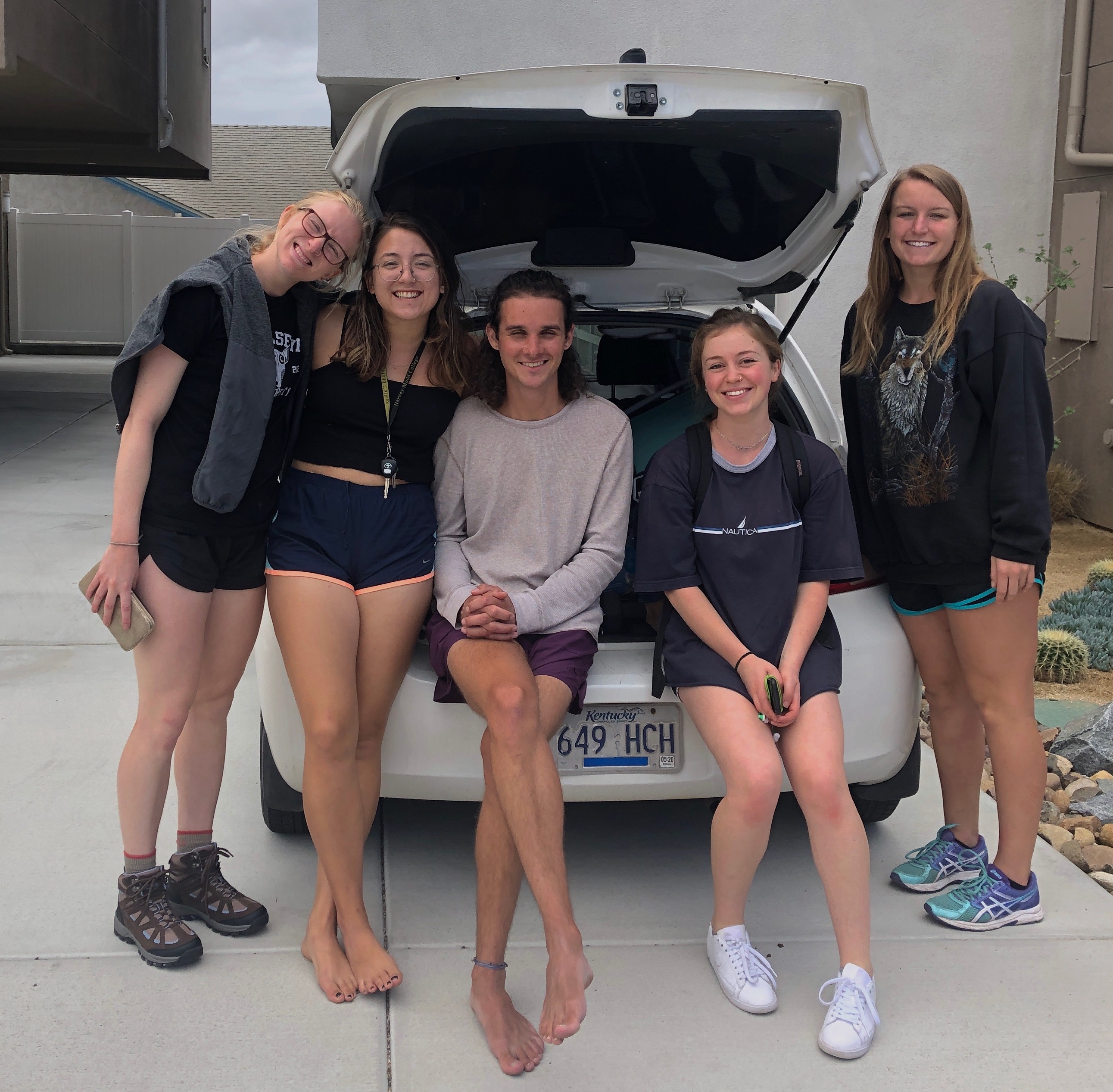Me and my four other friends sit at the tail of a car, smiling because we were about to head out on the trip!