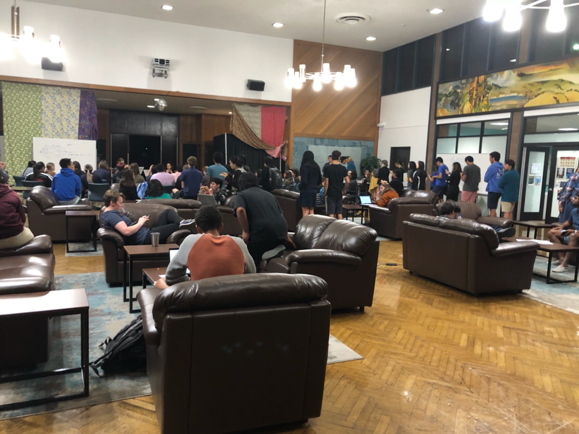 A room full of people and brown couches.