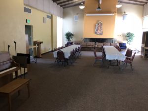 A large room with a piano on one side and two tables set up with chairs in the middle.