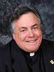 A priest in front of a gray background.