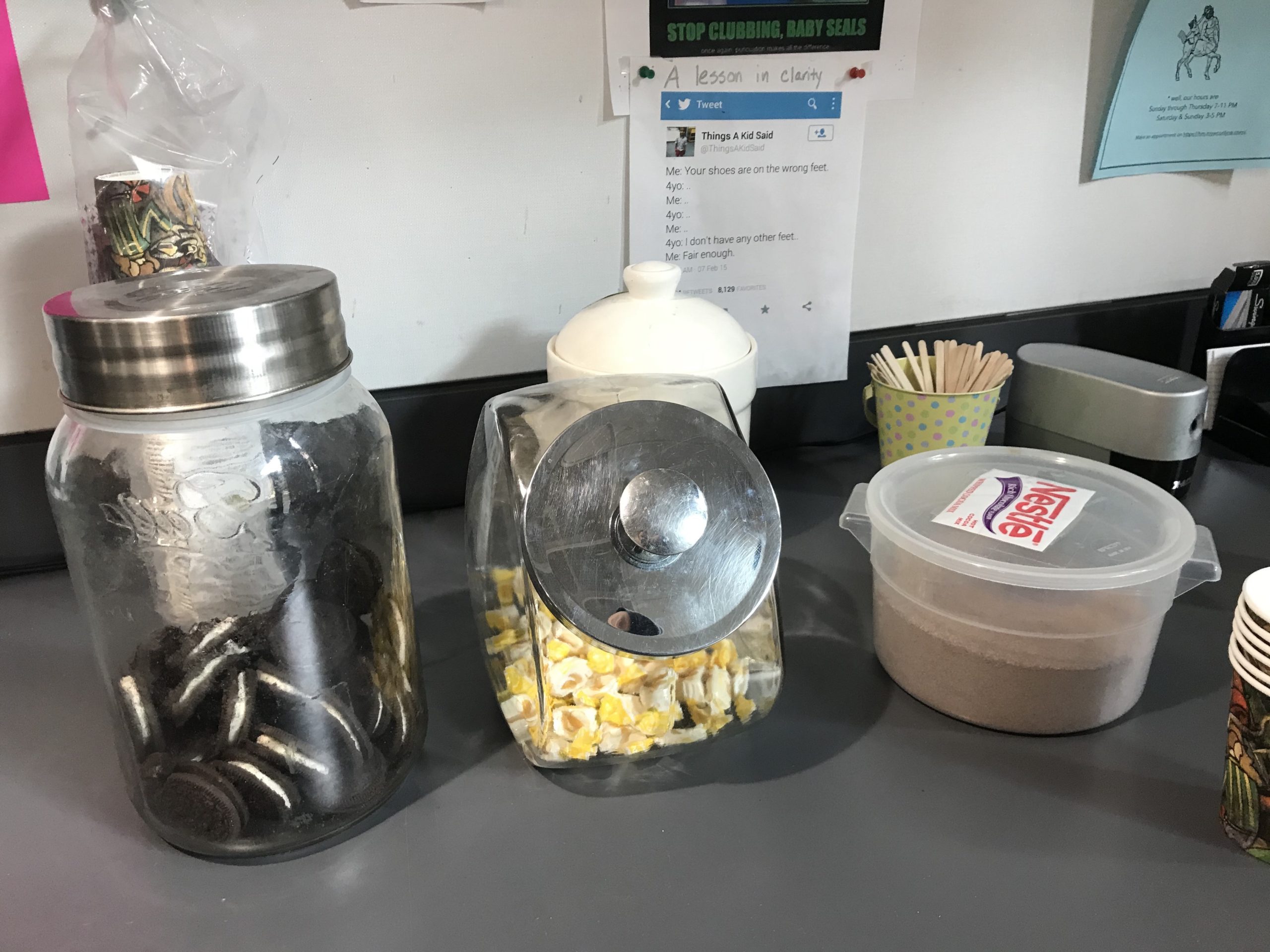 On the writing center counter sits a clear jar full of Oreos, a clear jar full of hard candies, and a plastic tub of hot chocolate.