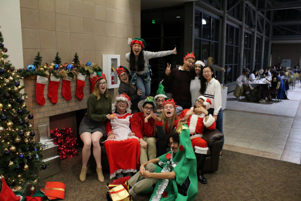A group of students dressed in festive attire posing with holiday decorations