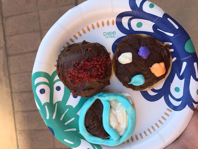 Three cookies, each decorated with brown frosting and colored lines/dots