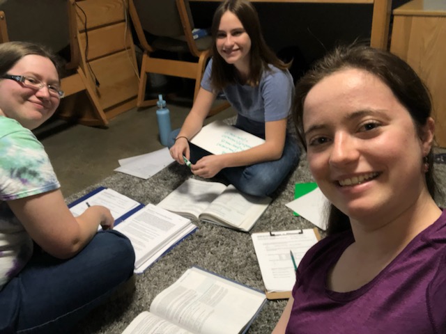 The three of us sitting in a circle on a rug with textbooks and paper