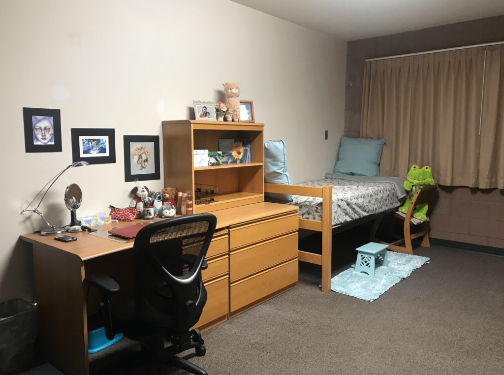 Desk, dresser, and bed set up with photos on the wall.