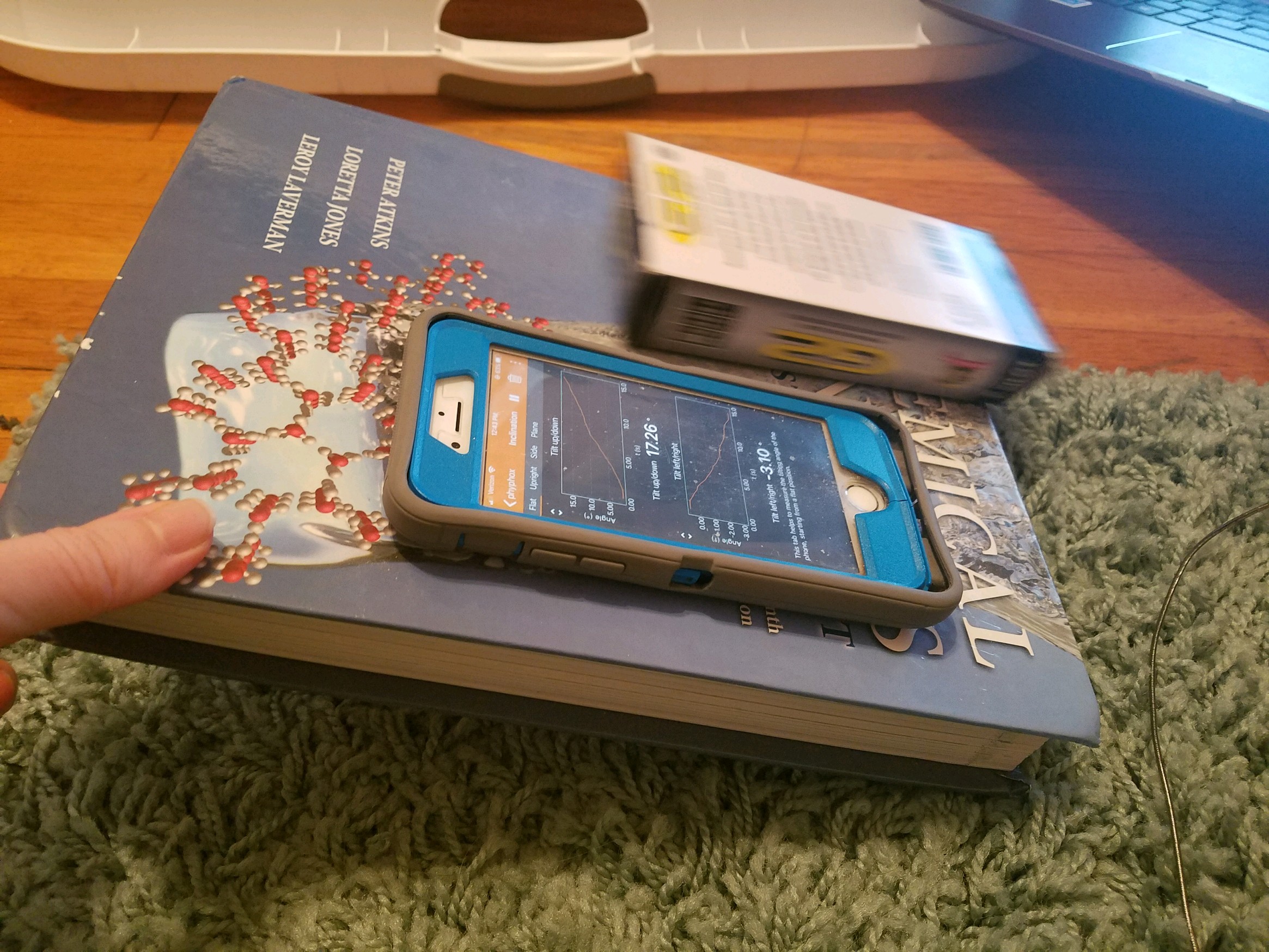 Phone and pen box on a tilted textbook.