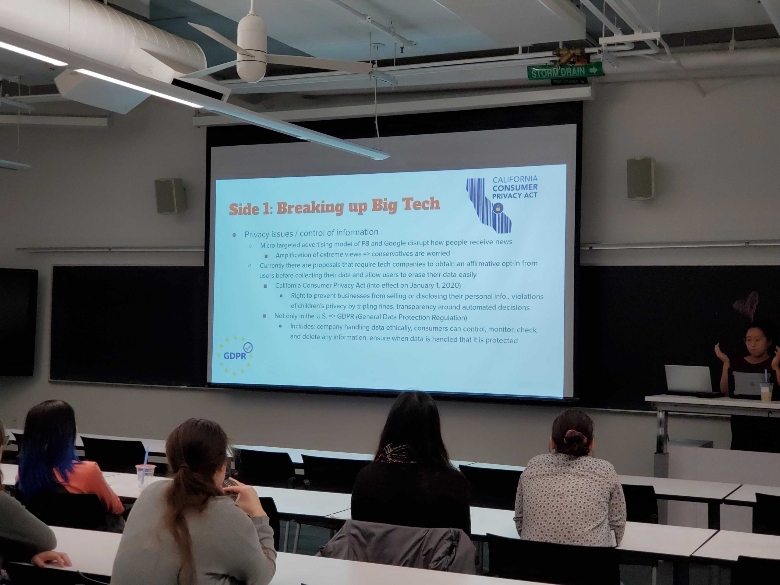 Students in a classroom watch a presentation with slides.