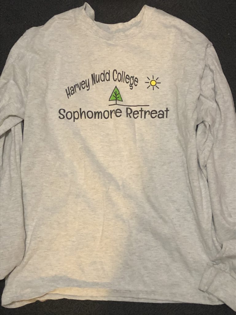 White long sleeve T-shirt with words "Harvey Mudd College Sophomore Retreat" and a cartoon pine tree.