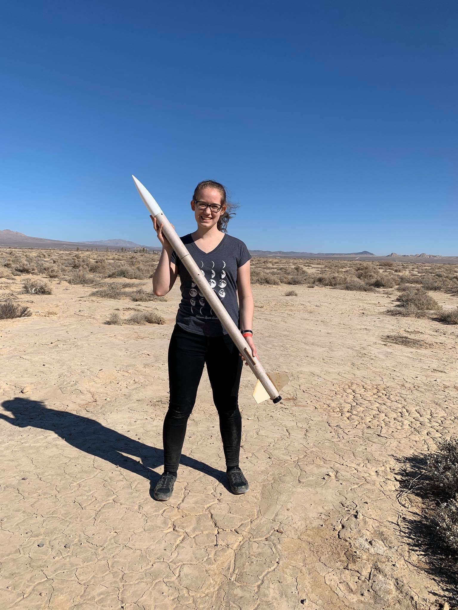 Katie, holding a rocket approximately her height.